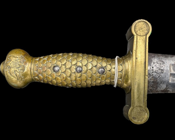 Details like the fish scale hilt, eagle on pommel, and maker’s mark can be seen.