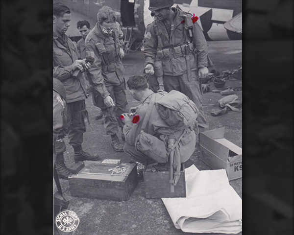 82nd Airborne paratroopers draw supplies before they board the planes from the ration crate to the left as well as a cardboard box (from a different crate) to the right.