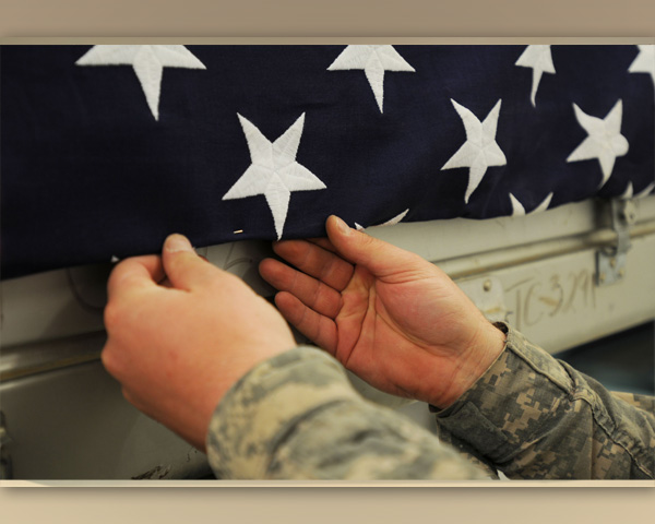 Mortuary Affairs Soldier affixing the U.S. flag over a transfer case.