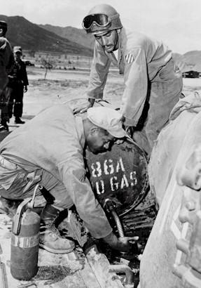 Two soldiers using a 55 gallon drum to fill an engine.