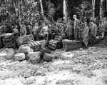 Soliders are strapping supplies to wooden pallets. Utilizing the pioneered “palletized unit loading” improvised by the “QM Imps”