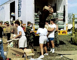 Soldiers and volunteers unload relief supplies from truck.